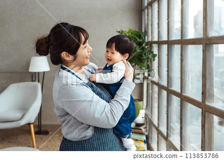 Side view of a mother holding her child while playing 113853786