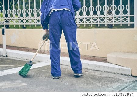 A municipal employee in a blue uniform collects garbage from roads and sidewalks. City cleaning Service with copy space. High quality photo 113853984
