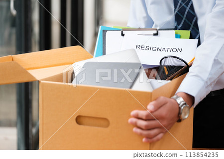 Man places personal items and resignation letter into a box, ending his tenure. 113854235