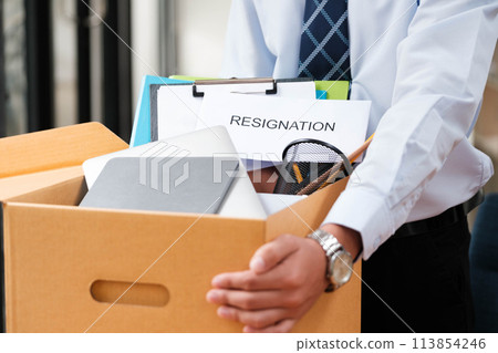 Man places personal items and resignation letter into a box, ending his tenure. 113854246