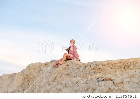 Teenager girl resting in nature, portrait of a girl sitting on the edge of a mountain 113854611