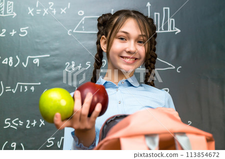Schoolgirl girl enjoys lunch of two ripe apples Schoolgirl girl enjoys lunch of two ripe apples 113854672