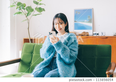 Woman using smartphone on sofa 113856054