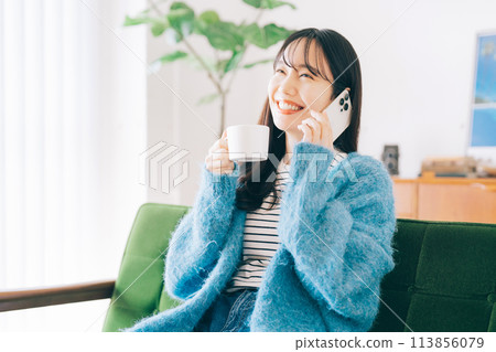 A woman who is calling on the sofa A woman who is calling on the sofa 113856079