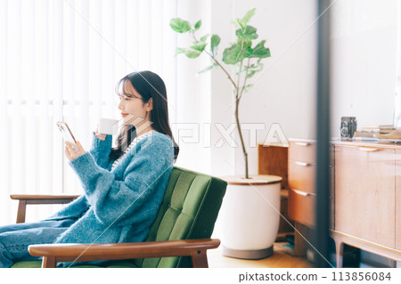 Woman using smartphone on sofa 113856084