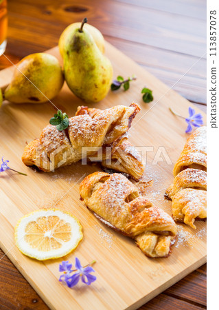 Sweet pastries, puff pastries with pears, on a wooden table Sweet pastries, puff pastries with pears, on a wooden table 113857078