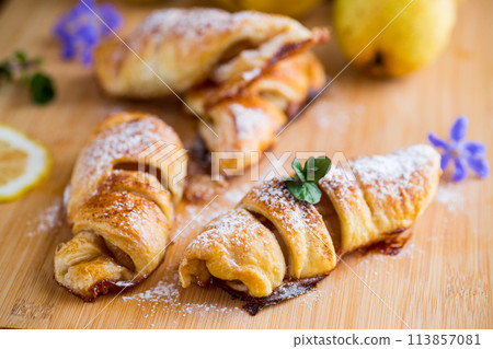 Sweet pastries, puff pastries with pears, on a wooden table Sweet pastries, puff pastries with pears, on a wooden table 113857081