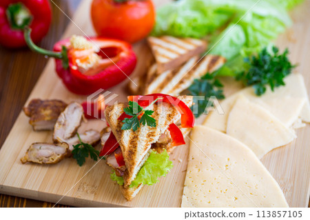 fried toast with chicken, salad, greens on a wooden table 113857105