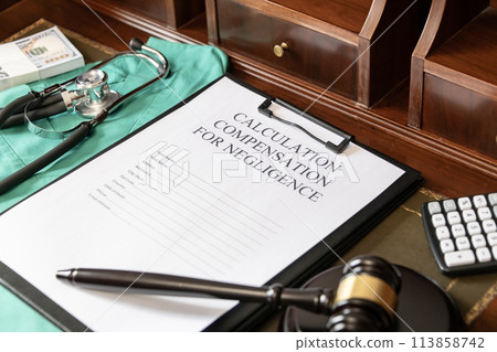 Document for calculating negligence compensation, with a stethoscope, money, and calculator on a medical uniform background. 113858742