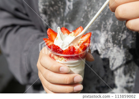 Hands of a young man eating a strawberry parfait 113859002