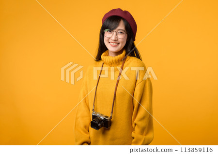 A young Asian woman, a camera enthusiast, wearing a yellow sweater and red beret, captures memories with her vintage camera against a vibrant yellow background. A young Asian woman, a camera enthusiast, wearing a yellow sweater and red beret, captures memories with her vintage camera against a vibrant yellow background. 113859116