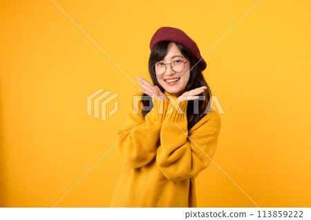 Joyful and a touch of shyness. A charming girl, donning a red beret and yellow sweater, expresses happiness against a vibrant yellow background. 113859222