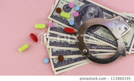 metal handcuffs with money and drugs on a pink background 113860195