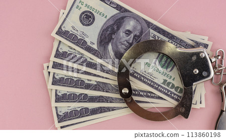 iron handcuffs and hundred dollar bills on a pink background iron handcuffs and hundred dollar bills on a pink background 113860198