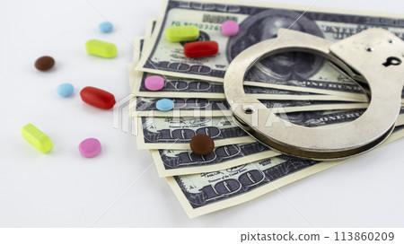 metal handcuffs with money and drugs on a white background metal handcuffs with money and drugs on a white background 113860209