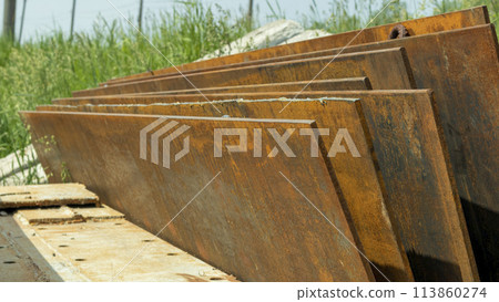 rusty iron sheets with loops are stacked on top of each other 113860274