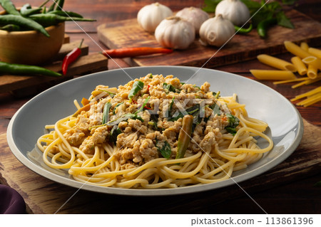 Stir fried spicy spaghetti with minced chicken breast and basil leaves in white plate,Spicy pasta Pad Kra Pao.Healthy Thai fusion food 113861396