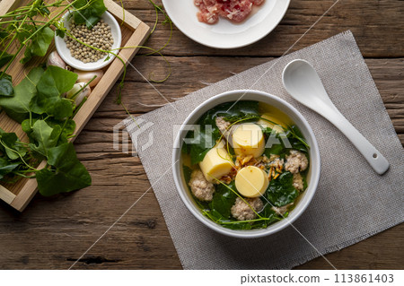 Clear Ivy gourd soup with minced pork and egg tofu in white bowl on wooden table,Thai food.(gaeng jued tum luang).Top view 113861403