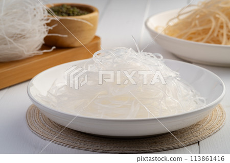 Fresh Glass Noodle in white plate with Dry Glass Noodle on wooden plate (Transparent bean vermicelli). 113861416