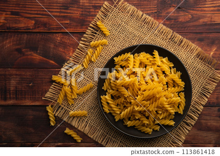 uncooked trivelle pasta in black plate on wooden table.top view uncooked trivelle pasta in black plate on wooden table.top view 113861418