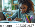 happy dark-skinned woman drawing with pencils in colouring book 113861987
