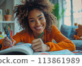 happy dark-skinned woman drawing with pencils in colouring book 113861989