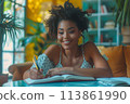 happy dark-skinned woman drawing with pencils in colouring book 113861990