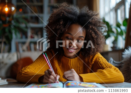 happy dark-skinned woman drawing with pencils in colouring book happy dark-skinned woman drawing with pencils in colouring book 113861993