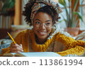 happy dark-skinned woman drawing with pencils in colouring book 113861994