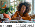 happy dark-skinned woman drawing with pencils in colouring book 113861998