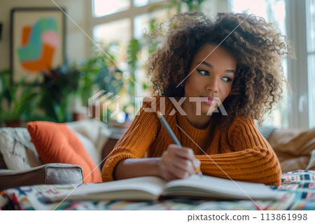 happy dark-skinned woman drawing with pencils in colouring book 113861998