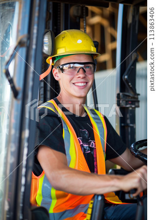 A Caucasian male employee is driving a forklift in a factory. 113863406