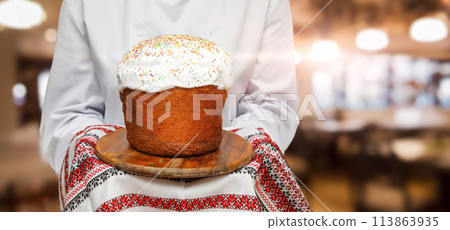 Cook shows Easter cake on towel with embroidery. 113863935