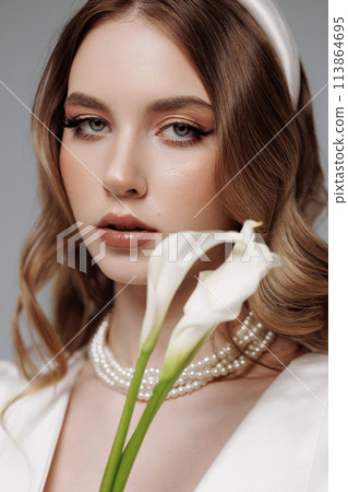 A woman with long brown hair and a white flower in her mouth 113864695