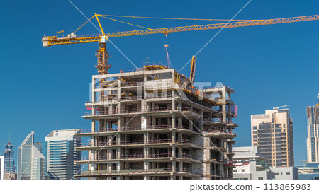Aerial view of a skyscrapers under construction with huge cranes timelapse in Dubai. 113865983