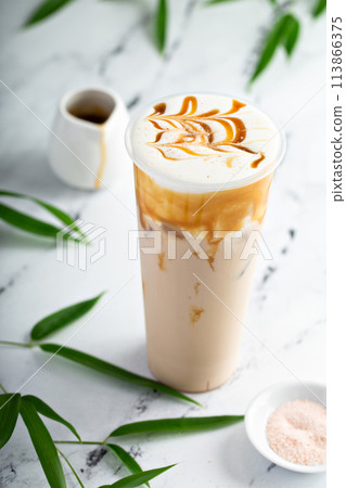 Caramel milk tea latte in a tall glass with cold foam and caramel sauce 113866375