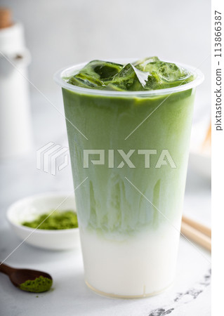 Matcha iced latte in a tall glass with matcha tea over milk 113866387