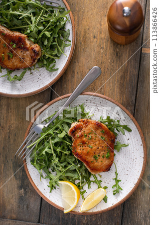 Pork chops served with arugula salad on a plate Pork chops served with arugula salad on a plate 113866426