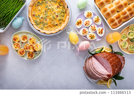 Easter brunch on large table with spiral sliced ham, quiche, deviled eggs and hot cross buns Easter brunch on large table with spiral sliced ham, quiche, deviled eggs and hot cross buns 113866513