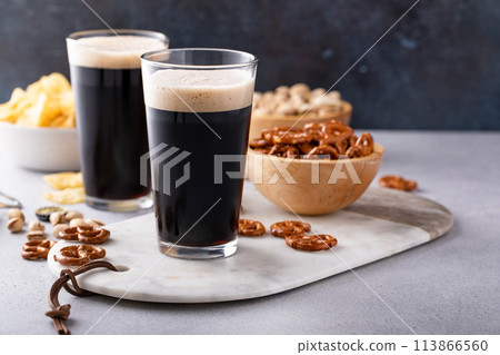 Dark stout beer in tall glasses with snacks 113866560