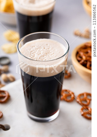 Dark stout beer in tall glasses with snacks 113866562
