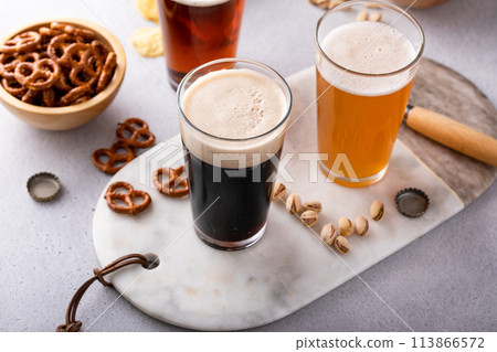 Dark stout, lager and ale beer in tall glasses on the table with snacks 113866572