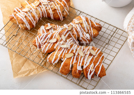 Bear claws pastry topped with glaze and almonds 113866585