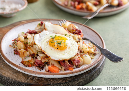 Corned beef hash with potatoes and carrots with fried egg on top 113866658