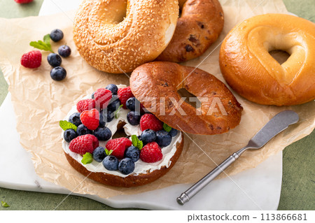 Cinnamon raisin bagel topped with cream cheese and fresh berries 113866681
