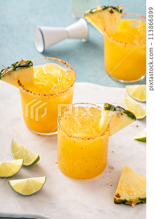 Pineapple margarita with spicy rim and lime wedges Pineapple margarita with spicy rim and lime wedges 113866899