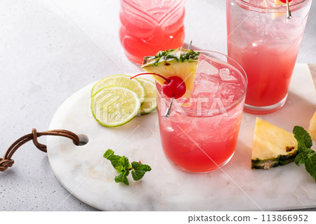 Singapore sling cocktails in a variety of glasses garnished with pineapple and cherry Singapore sling cocktails in a variety of glasses garnished with pineapple and cherry 113866952