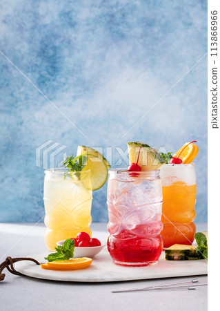 Variety of tropical tiki cocktails with cold foam, garnished with orange slices, cherry and mint 113866966