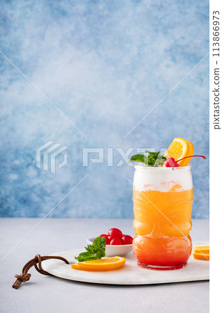 Tropical tiki cocktail with cold foam, garnished with orange slices, cherry and mint Tropical tiki cocktail with cold foam, garnished with orange slices, cherry and mint 113866973