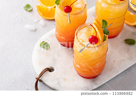 Hurricane cocktail in tiki glasses, tropical, rum-based cocktail with orange and cherry for garnish Hurricane cocktail in tiki glasses, tropical, rum-based cocktail with orange and cherry for garnish 113866982